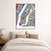 Colorful Manhattan map art print on a wall above a bed.