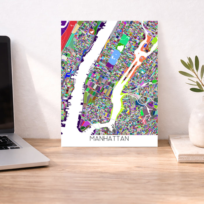 Colorful Manhattan map poster on a desk with a laptop and plant.