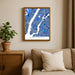 Framed map of Manhattan on a wall above a beige sofa with a plant beside it.