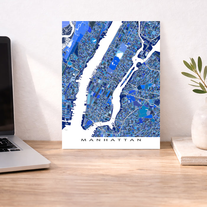 Manhattan map poster on a desk with a laptop and plant