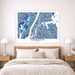 Framed map of Manhattan on a wall above a bed with nightstands and lamps.