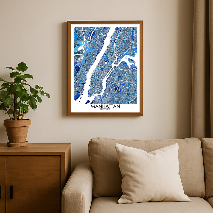 Framed map of Manhattan on a wall above a beige sofa with a plant beside it.