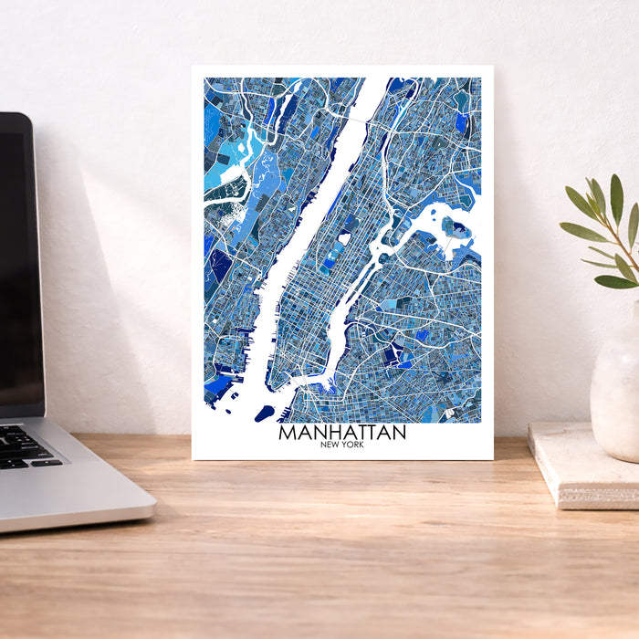 Manhattan map poster on a desk with a laptop and plant