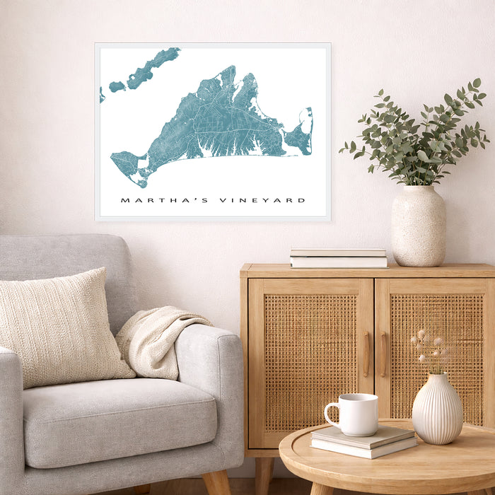 Living room with a map of Martha's Vineyard on the wall, a couch, and a side table with a vase and books.