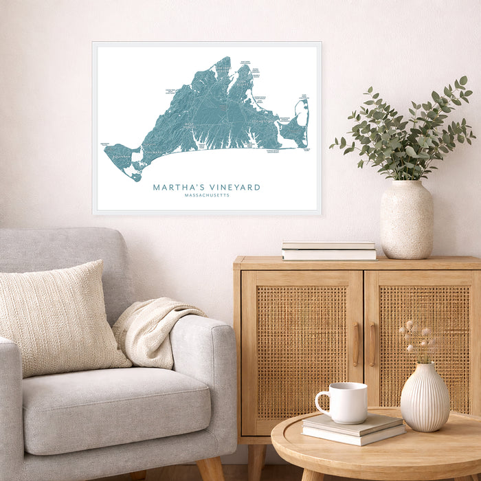 Living room with a map of Martha's Vineyard on the wall, a couch, and a side table with a vase and books.