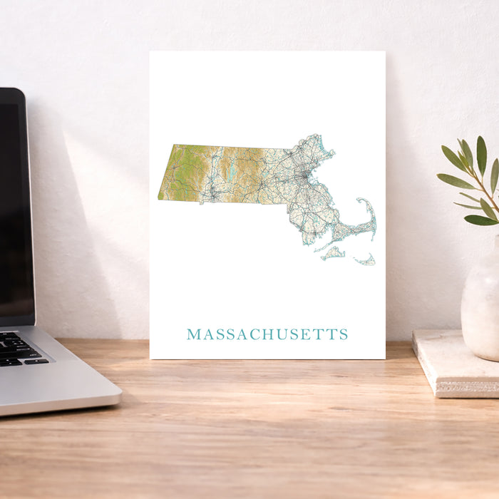 Map of Massachusetts on a desk with a laptop and plant