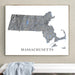 Framed map of Massachusetts on a wall above a white surface with a gray towel.