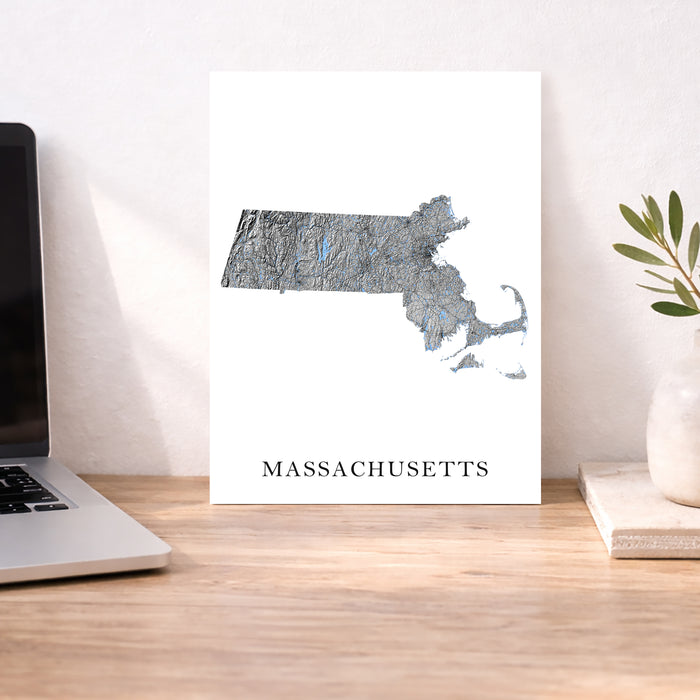 Map of Massachusetts on a desk with a laptop and plant