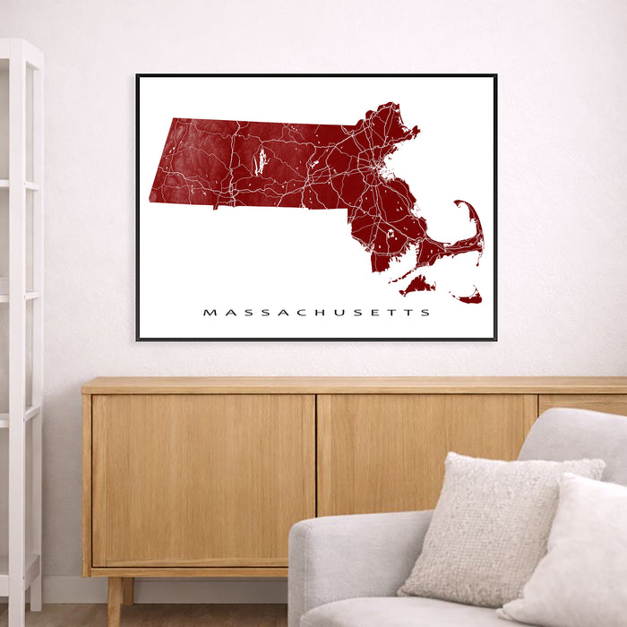 Map of Massachusetts framed on a wall above a wooden cabinet and gray sofa.