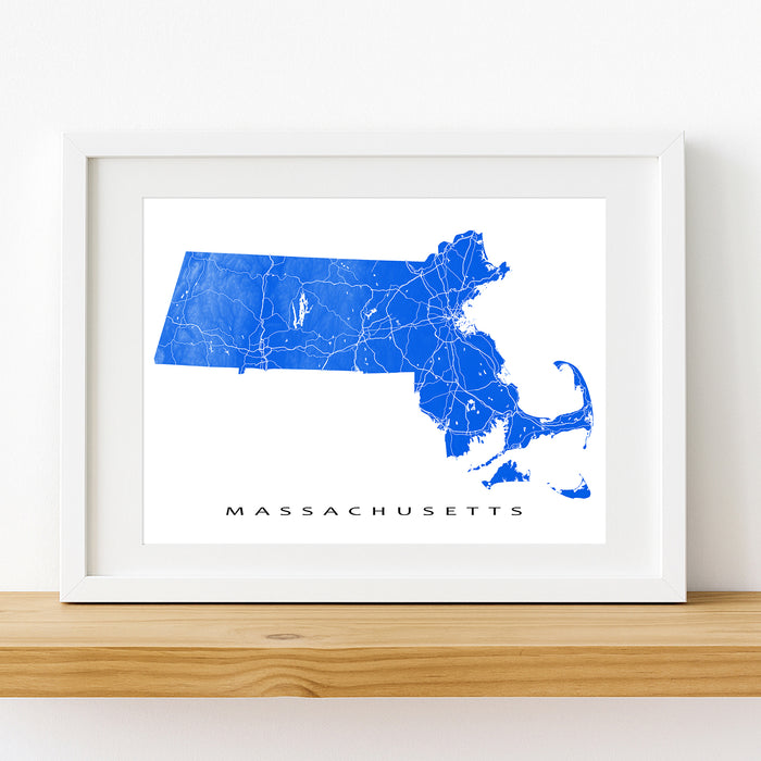Framed map of Massachusetts on a white wall with a wooden shelf.