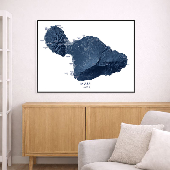 Framed map of Maui, Hawaii on a wall above a wooden cabinet and white sofa.
