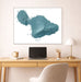Framed map of Maui, Hawaii on a wall above a desk with a laptop and lamp.