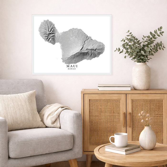 Living room with a framed map of Maui on the wall, a light gray sofa, wooden cabinet, and decorative items.