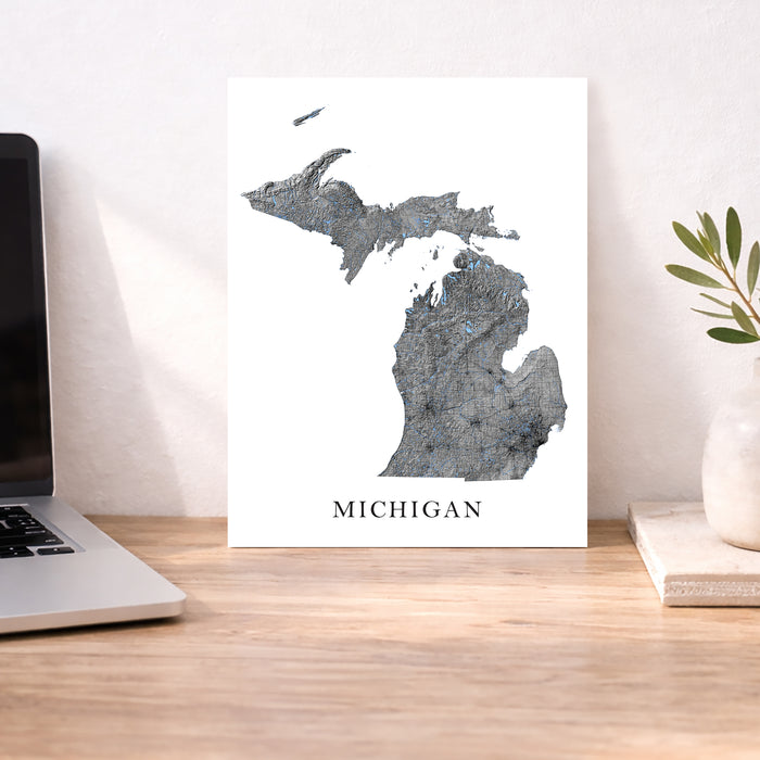 Map of Michigan on a desk with a laptop and plant