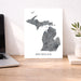 Map of Michigan on a desk with a laptop and plant
