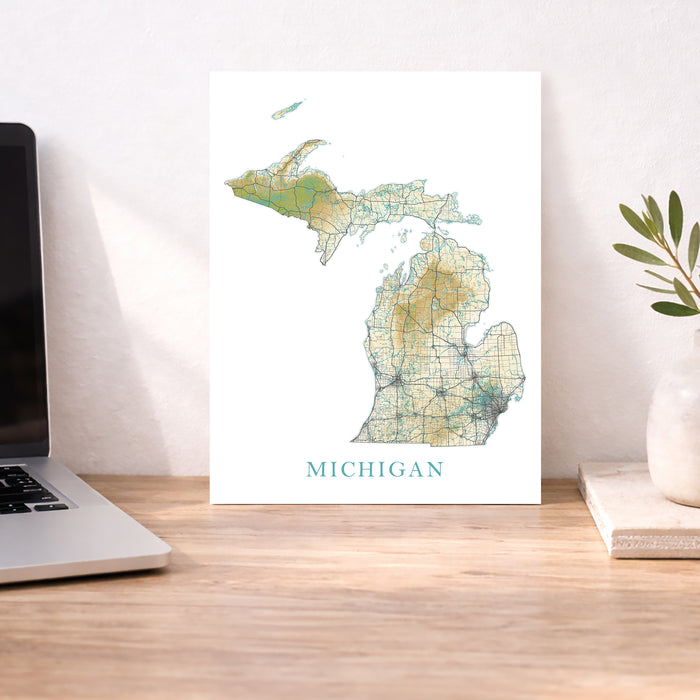 Map of Michigan on a desk with a laptop and plant