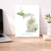 Map of Michigan on a desk with a laptop and plant