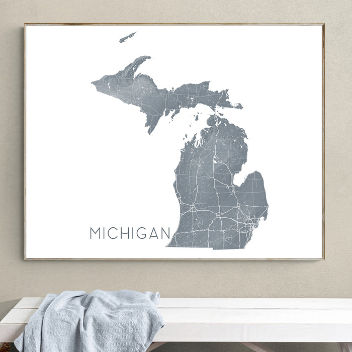 Framed map of Michigan on a wall above a white bench.