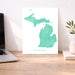 Map of Michigan on a white background next to a laptop on a wooden desk.