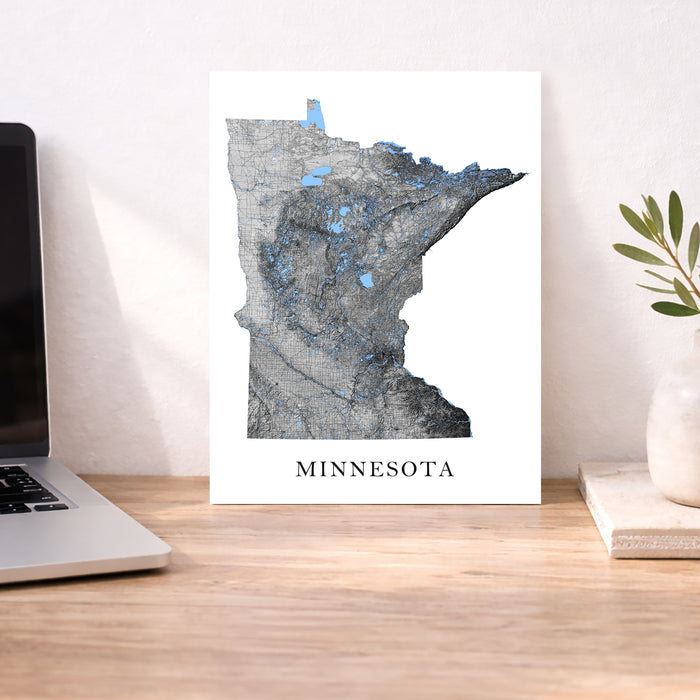 Map of Minnesota on a desk with a laptop and plant