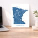 Map of Minnesota on a white background next to a laptop on a wooden desk.