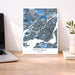 Map of Montreal on a wall above a desk with a laptop and plant.