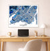 Framed map of Montreal on a wall above a desk with a laptop and office items.