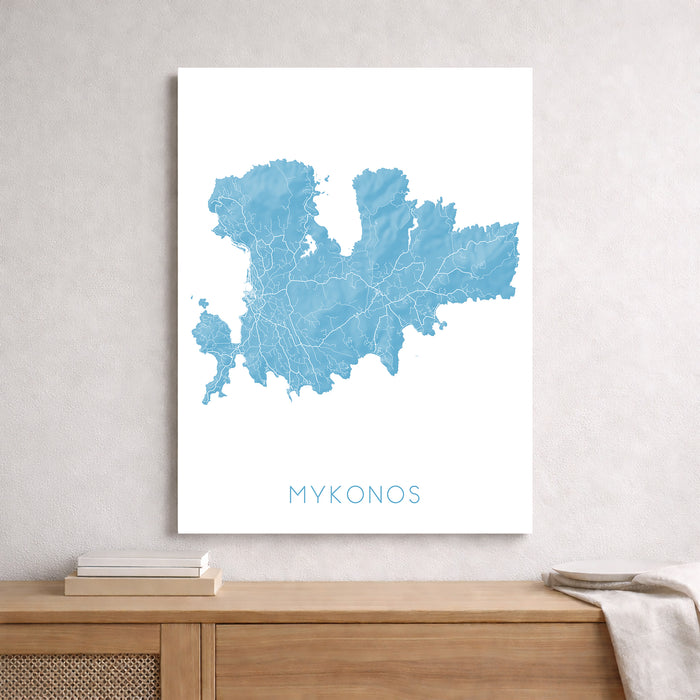 Map of Mykonos on a white wall above a wooden shelf.