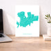 Map of Mykonos on a white background next to a laptop on a wooden desk.