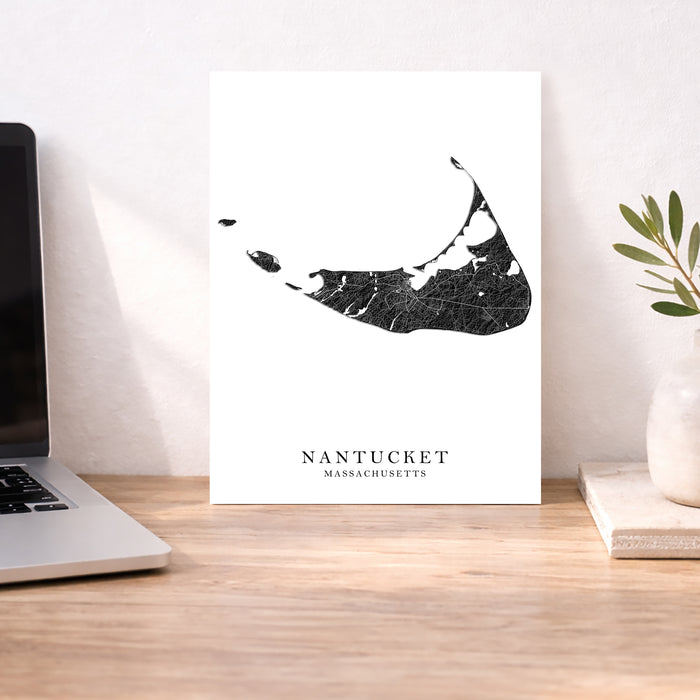 Map of Nantucket, Massachusetts on a white background next to a laptop on a wooden desk.