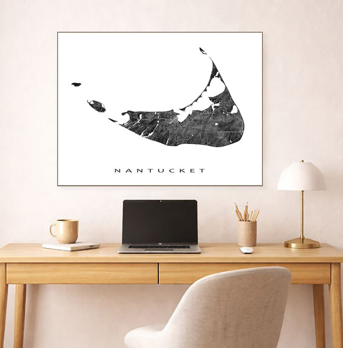 Framed map of Nantucket above a desk with a laptop and lamp.