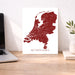 Map of the Netherlands on a white background next to a laptop on a wooden desk.