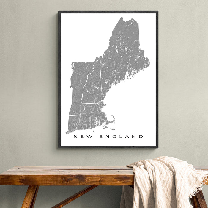 Framed map of New England on a wall above a wooden bench.