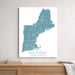 Map of New England on a white wall above a wooden shelf.