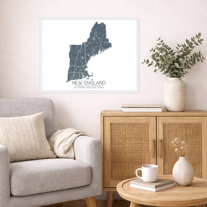 Living room with a map of New England on the wall, a couch, and a side table with a vase and books.