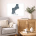 Living room with a map of New England on the wall, a couch, and a side table with a vase and books.