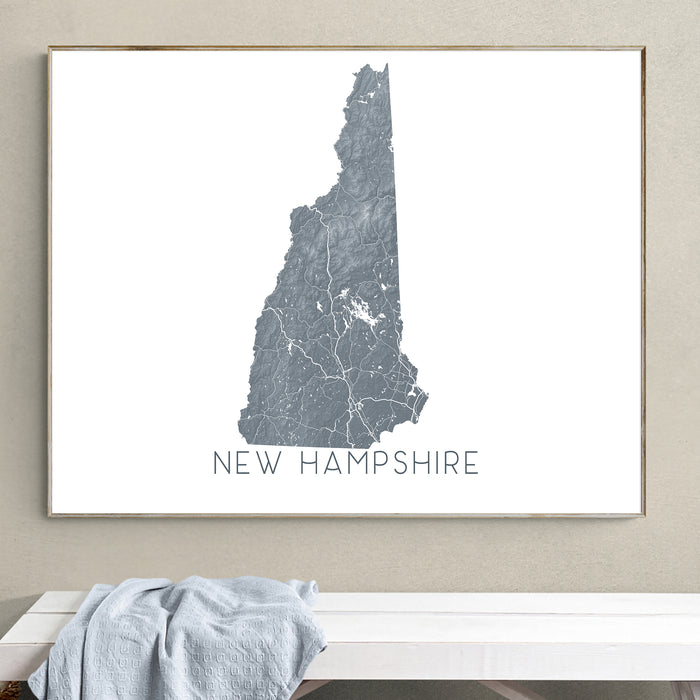 Framed map of New Hampshire on a wall above a white bench.