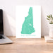 Map of New Hampshire on a desk with a laptop and plant
