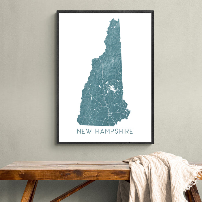 Framed map of New Hampshire on a wall above a wooden bench.