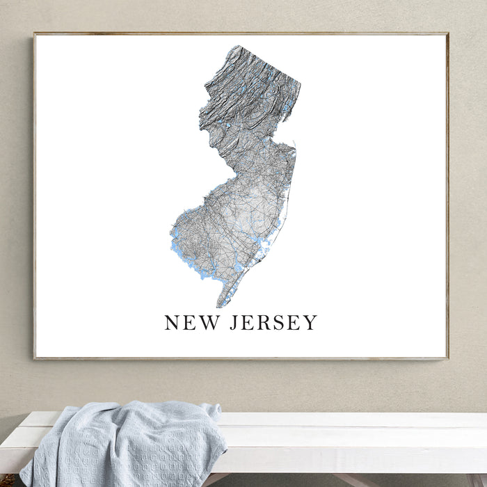 Framed map of New Jersey on a wall above a white bench.