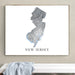 Framed map of New Jersey on a wall above a white bench.