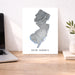 Map of New Jersey on a desk with a laptop and plant