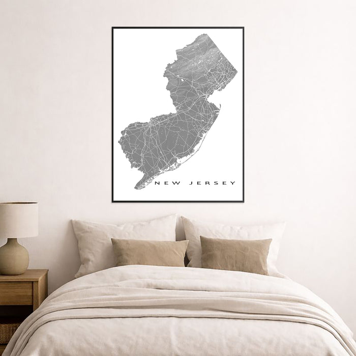 Framed map of New Jersey on a wall above a bed in a bedroom.
