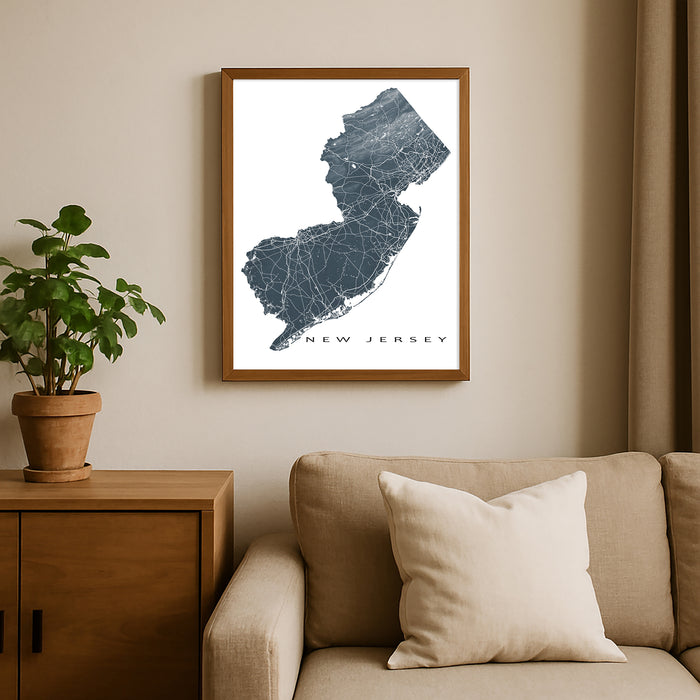 Framed map of New Jersey on a wall above a beige sofa with a plant beside it.