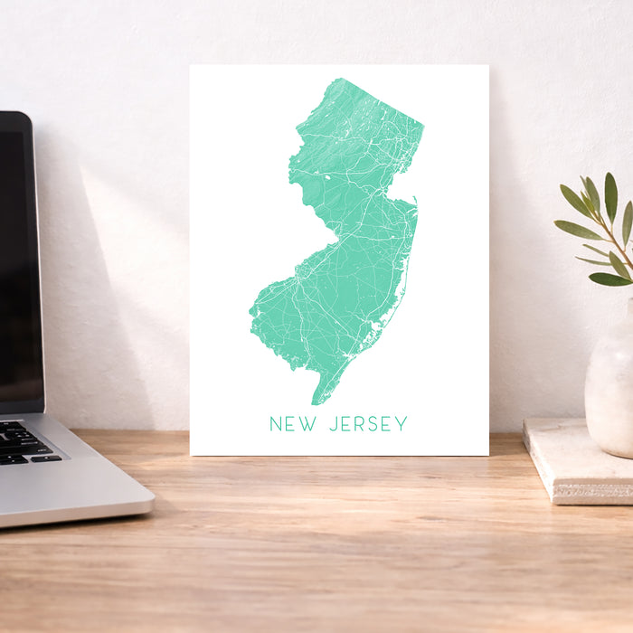 Map of New Jersey on a desk with a laptop and plant