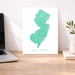 Map of New Jersey on a desk with a laptop and plant