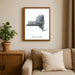 Framed New York map art print on a wall above a sofa with a plant beside it.
