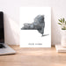 Map of New York on a white background next to a laptop on a wooden desk.