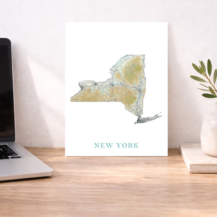 Map of New York on a desk with a laptop and plant