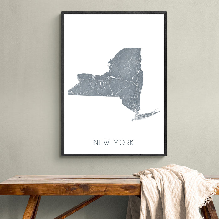 Framed map of New York on a wall above a wooden bench.